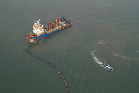 Monster, Netherlands - 13 February 2026: Aerial view of two ships sailing on the water, one leaving a trail of sediment, contrasting against the calm, dark sea.