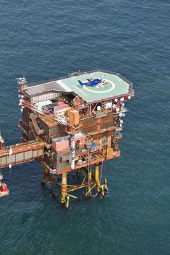 United Kingdom, United Kingdom - 15 February 2026: Aerial view of a blue helicopter resting on the helipad of an offshore platform, surrounded by the deep blue sea.