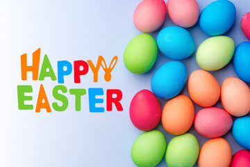 Fototapeta premium Colorful eggs and happy easter greeting on light background for holiday celebration