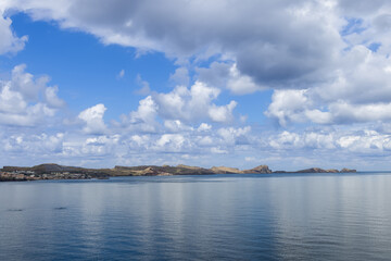 Point of Saint Lawrence Madeira panoramic Atlantic coastline from base to far tip, wide seascape showing calm water layered clouds distant hills and the full volcanic headland profile
