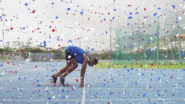 Male sprinter launching from blocks on start cue into sprint down blue track with confetti overlay