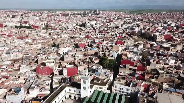 Comprehensive drone shot showcasing the dense residential fabric of Larache. Features the mix of old and new architecture, the Grand Mosque minaret, and the vast urban expansion over the hills.