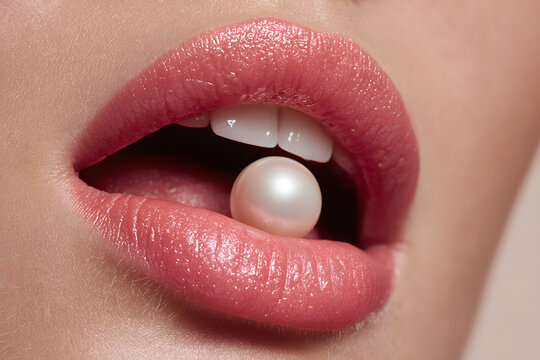 Lips hold a pearl between them, showing off beauty and fashion in a close view with soft lighting