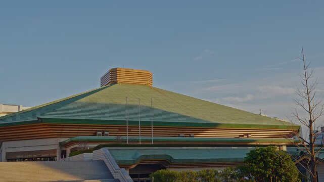 A clear daytime shot of the distinctive green roof of Ryogoku Kokugikan, Japan's premier Sumo wrestling arena, located in the Ryogoku district of Tokyo.