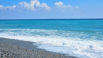 Obraz premium Hualien pebble beach with rolling ocean waves and rhythmic stone shoreline textures, soothing coastal atmosphere under expansive blue sky along Taiwan eastern Pacific coast