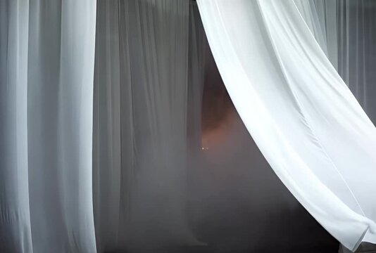 Flowing white fabric draping gracefully in an indoor setting creating a serene and soft atmosphere with gentle light filtering through