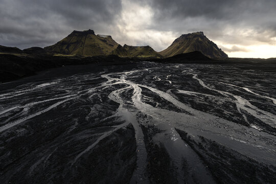 View of stark black sands etched with silver streams under a brooding sky, framed by towering peaks in the distance, Reykjav&Atilde;&shy;k, Reykjav&Atilde;&shy;kurborg, Iceland.