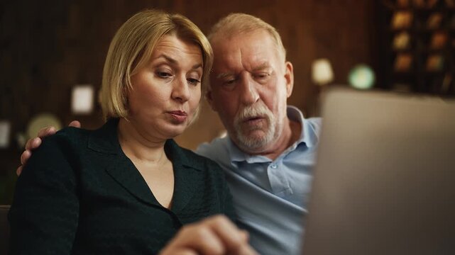 Adult daughter teaching senior dad how to use laptop software, family time
