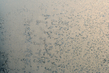 Fototapeta premium Frost on glass with warm light winter abstract background