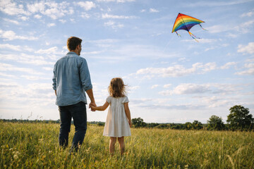 Father and daughter holding hands watching kite