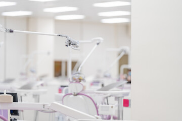 The side view of a modern white dental light lamp and reflector equipment above a medical chair on...