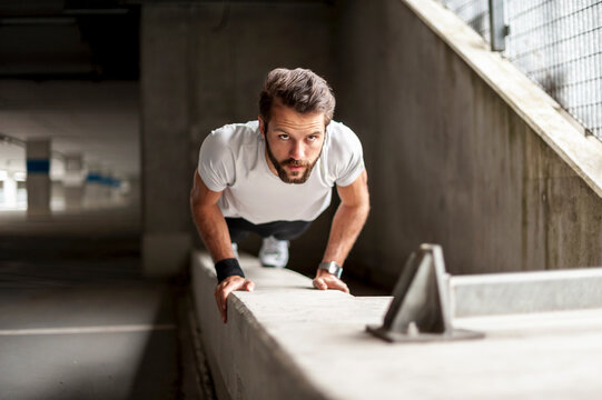 Person doing push up exercise outdoors on urban concrete structure