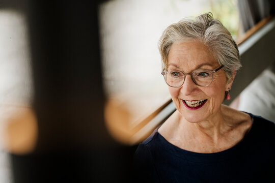 Smiling senior woman with glasses enjoying time at cafe indoors