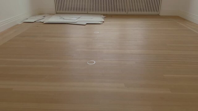 Wooden floor at gallery room with big window. White temporary floor on the corner during dismantling process