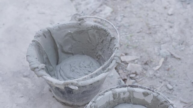 Close up of fresh cement mortar being poured and mixed in bucket at construction site. Building renovation, masonry preparation and industrial material concept.