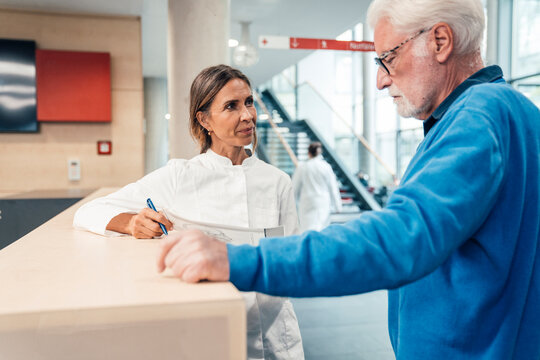 Doctor consulting patient at hospital reception desk