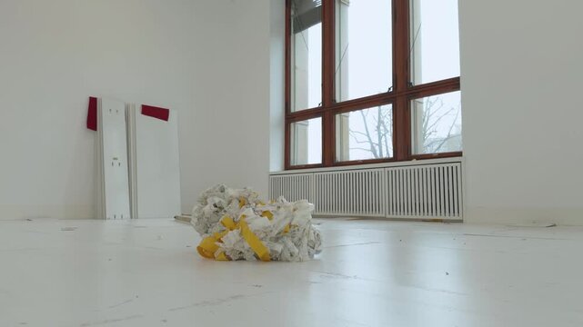 Gallery space with big windows during dismantling process with temporary white floor and doble-sided tape residue.