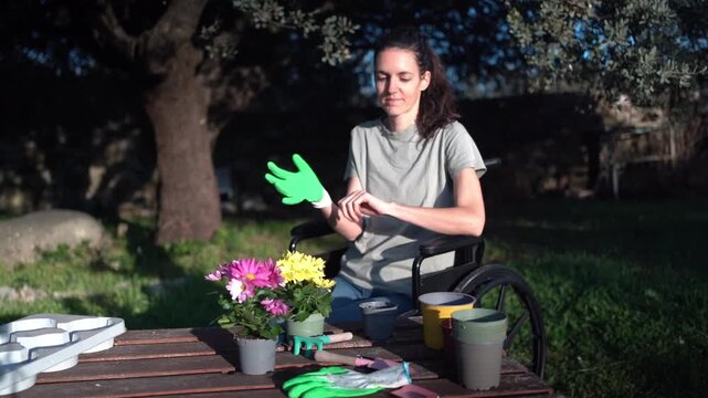Disabled woman in wheelchair wearing gardening gloves