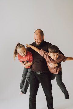 Father playing with children and hugging them in studio