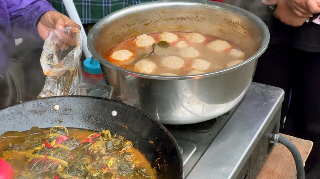 Indonesian traditional spicy food buntil and meatballs being cooked in a large pot