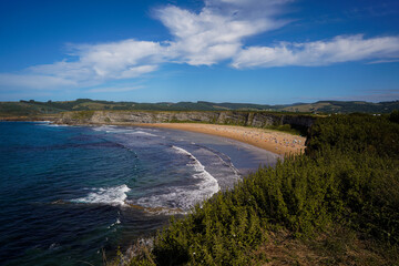 High angle view of a crowded sandy beach surrounded by green cliffs.