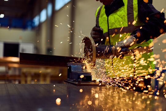 Industrial Worker Grinding Steel With Angle Grinder in Factory Workshop Wearing High Visibility Vest