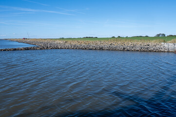 View from the North Sea towards the coast with stone wall, meadow and some trees