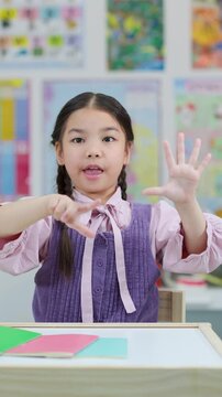 Young Girl Counting on Fingers in Classroom Setting