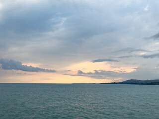 Fototapeta premium Sunset at Issyk Kul Lake in Kyrgyzstan. Bright sun breaking through clouds reflecting in clear turquoise water.