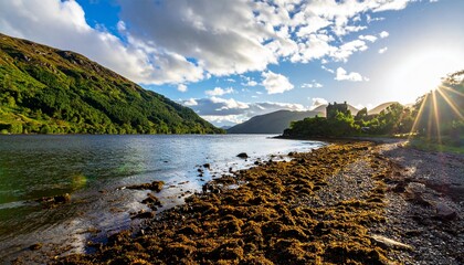 Historic Scottish castle on a tranquil loch shore with dramatic sunbeams