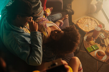 Obraz premium Retro friends cuddling on a couch during a cozy 90s movie night with pizza and games