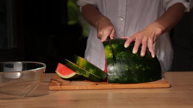 Cutting watermelon in the kitchen during the evening