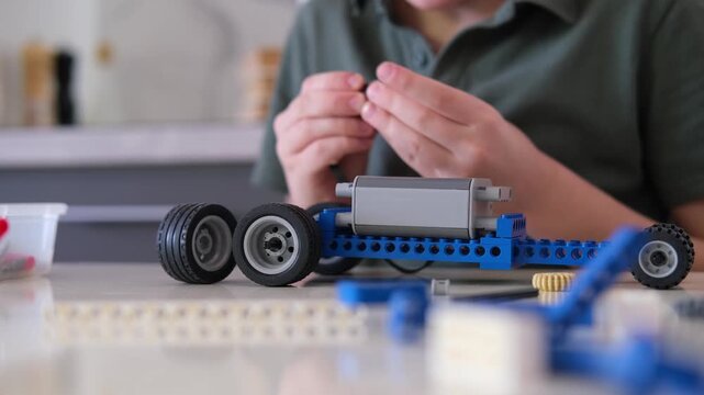  boy builds a toy robot car using his imagination. Robotics, children's technology, robot construction kit, educational toy.