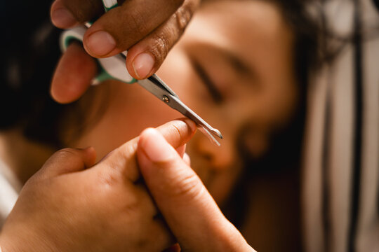 close up of mother cutting baby nails, concept of manicure on children and hygiene care, real authentic scene