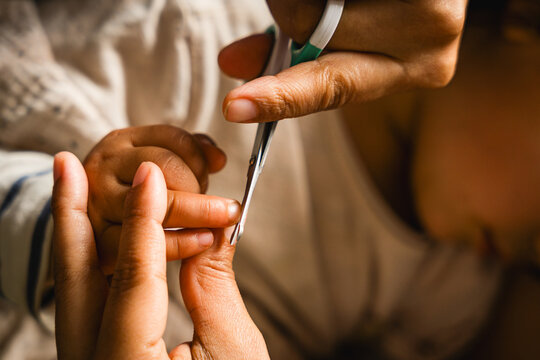 close up of mother cutting baby nails, concept of manicure on children and hygiene care, real authentic scene