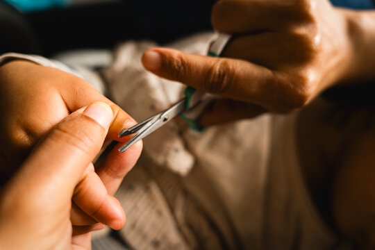 close up of mother cutting baby nails, concept of manicure on children and hygiene care, real authentic scene