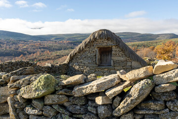 A stone wall with a small house on top of it