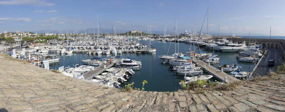 View of a vibrant harbor filled with yachts and boats bobbing gently on the turquoise water under a clear sky, Antibes, Provence-Alpes-Cote d'Azur, France.