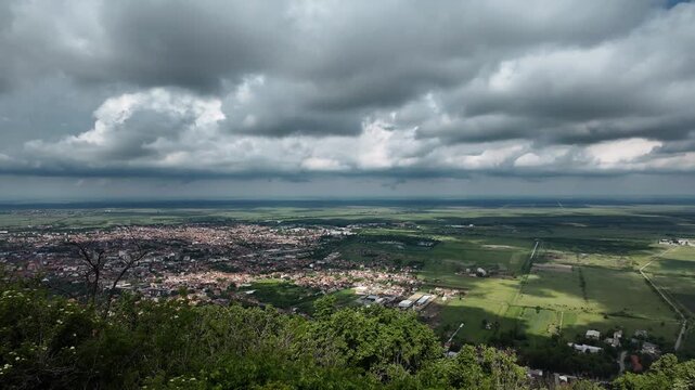 Panoramic view of Vrsac and surrounding plains from the hilltop in Serbia. Dramatic clouds cast shadows over farmland and town under a wide Balkan sky