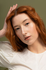 Fototapeta premium Elegant redhead young woman shines in stylish spring attire within a studio setting