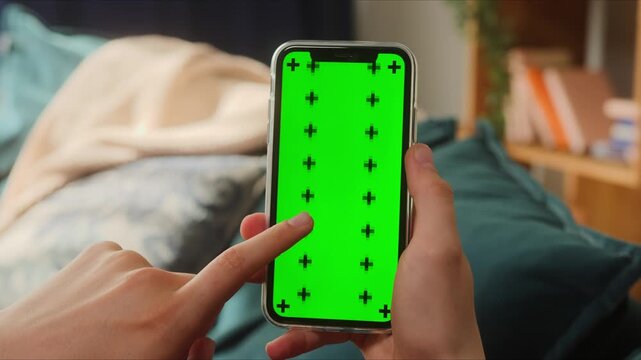 Hands holding a smartphone with a green screen and tracking markers for editing, 4K animated visual for modern digital content.