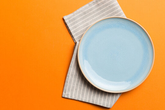 Top view on colored background empty round blue plate on tablecloth for food. Empty dish on napkin with space for your design
