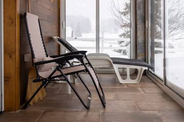 Cozy Mountain Lodge Interior with Folding Deckchair and Snowy Terrace View.