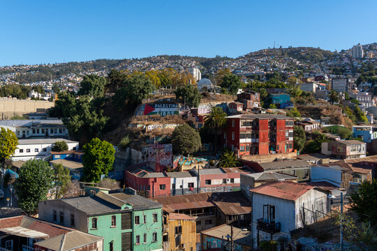 View of weathered colorful buildings cascade down the hillsides, a vibrant tapestry under a clear sky, capturing the essence of urban life, Valparaiso, Valparaiso, Chile.