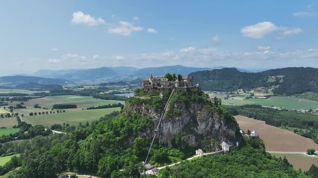 Cinematic drone footage capturing Hochosterwitz Castle on hilltop, fortified walls, dramatic cliffs, summer colors, sweeping aerial movement, historical landmark atmosphere