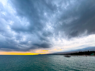 Sunset at Issyk Kul Lake in Kyrgyzstan. Bright sun breaking through clouds reflecting in clear turquoise water.