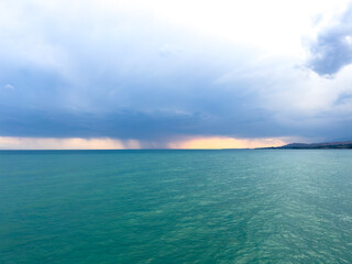 Obraz premium Sunset at Issyk Kul Lake in Kyrgyzstan. Bright sun breaking through clouds reflecting in clear turquoise water.