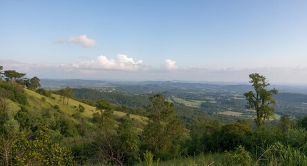 Fototapeta premium Picturesque elevated terrain with flourishing greenery and a calm sky backdrop