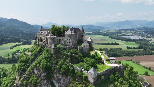 Cinematic drone footage capturing Hochosterwitz Castle on hilltop, fortified walls, dramatic cliffs, summer colors, sweeping aerial movement, historical landmark atmosphere