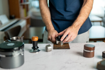 Obraz premium Man Tapping The Portafilter After Dosing Coffee Grounds In Kitchen